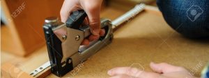 Worker repairing furniture with construction stapler